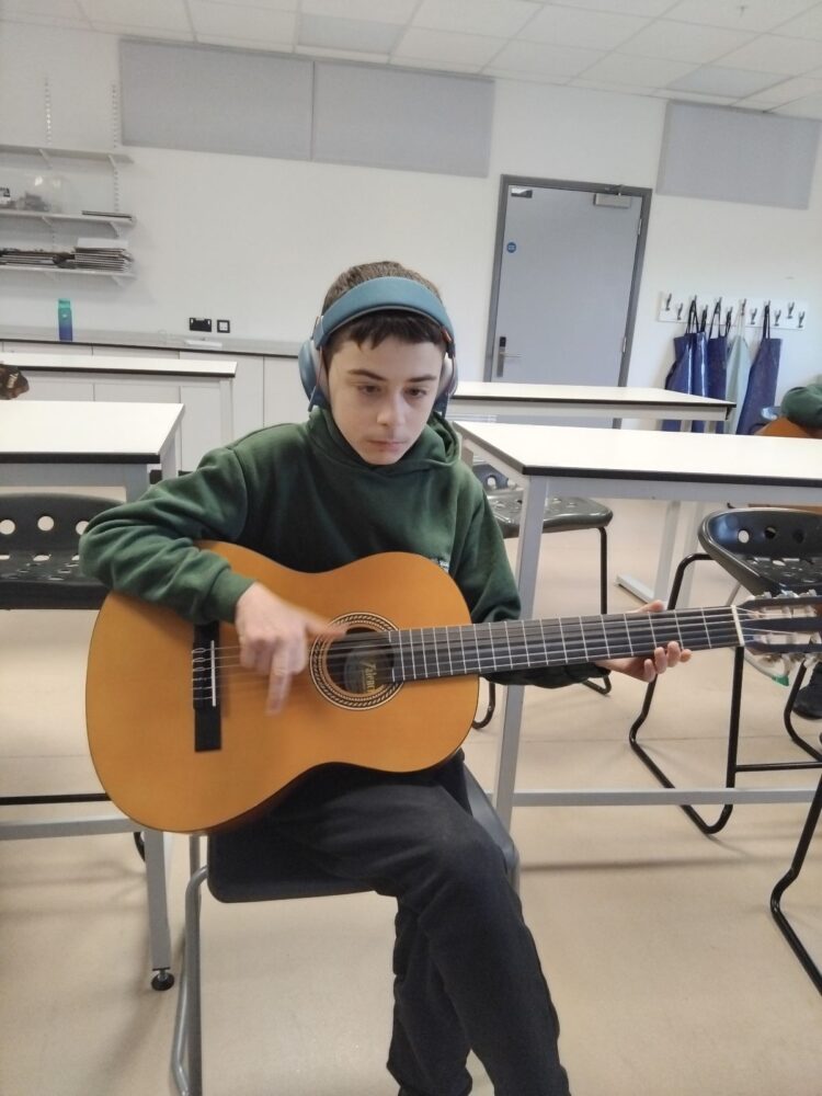 A student playing an acoustic guitar